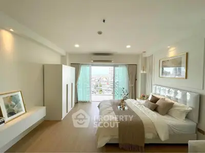 Spacious modern bedroom with balcony and city view, featuring elegant decor and natural light.