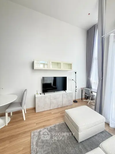 Modern living room with high ceilings, stylish furniture, and natural light from large windows.