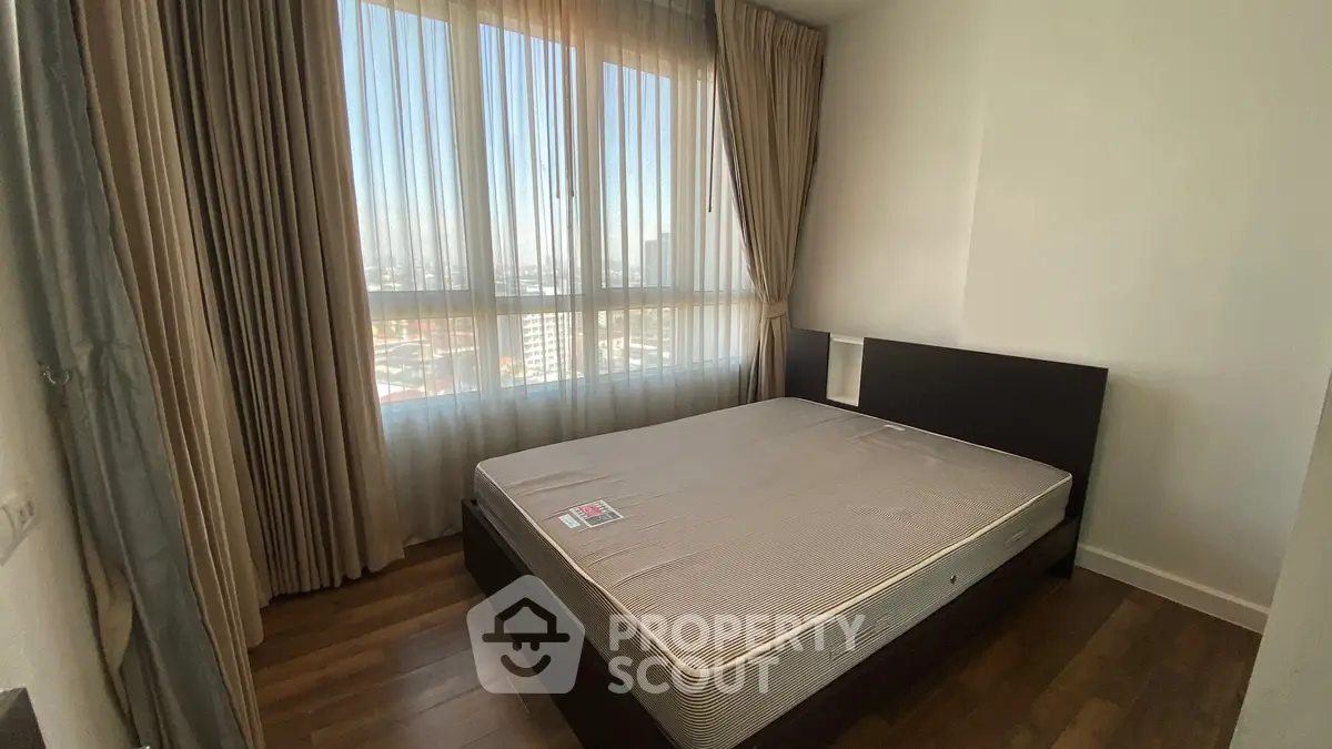 Spacious bedroom with large window and wooden flooring in modern apartment