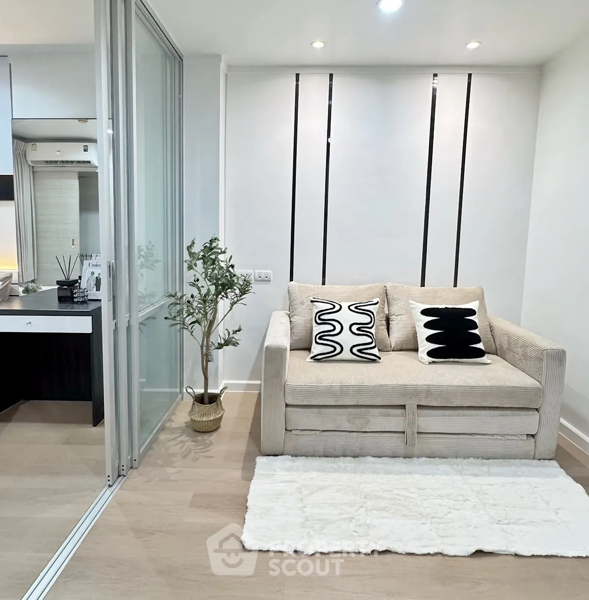 Modern living room with cozy beige sofa and stylish decor in a compact apartment.