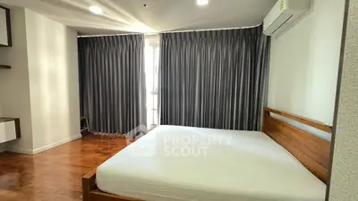 Spacious bedroom with wooden flooring and modern furnishings