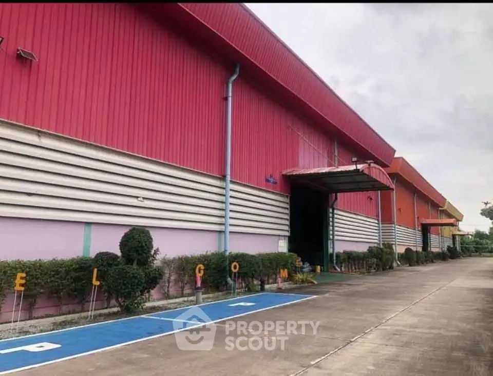 Spacious industrial warehouse with vibrant exterior and ample parking space.