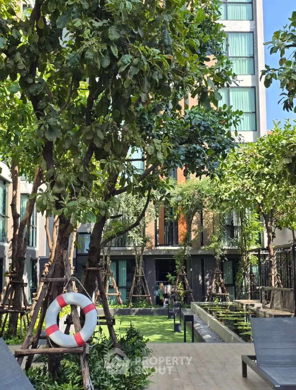 Lush garden area with trees and modern building backdrop, ideal for relaxation.