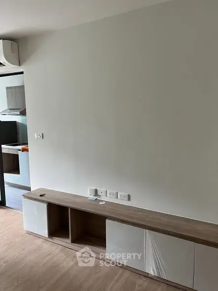 Modern minimalist living room with built-in storage and open kitchen view.