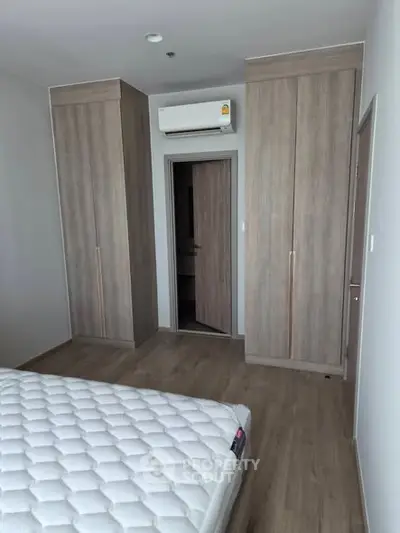 Modern bedroom with built-in wardrobes and air conditioning unit, featuring a comfortable mattress.