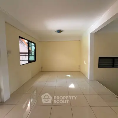 Spacious empty room with tiled flooring and large windows, perfect for customization.