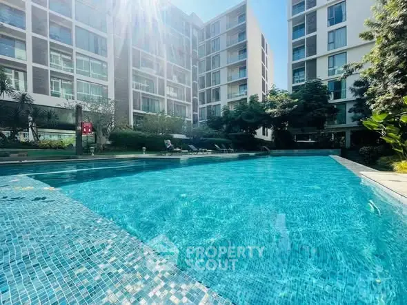 Luxurious apartment complex with a sparkling outdoor pool and lush greenery.
