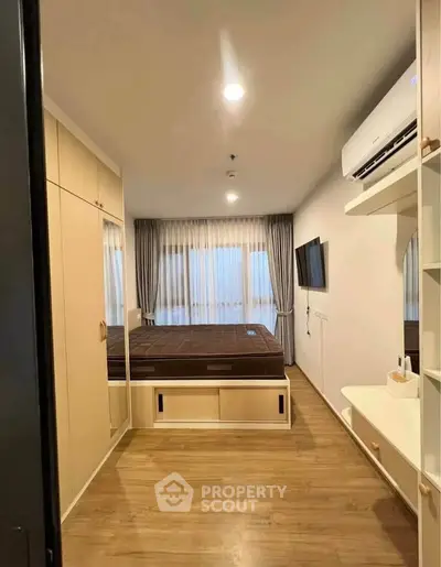 Modern bedroom with built-in wardrobe and air conditioning, featuring a sleek design and ample natural light.