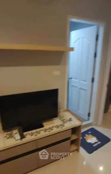 Cozy living room with TV and decorative shelf, ideal for relaxation.
