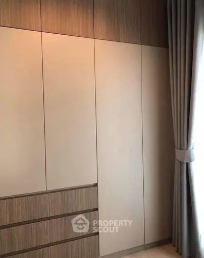 Modern minimalist wardrobe with sleek design and elegant curtains in a stylish bedroom.