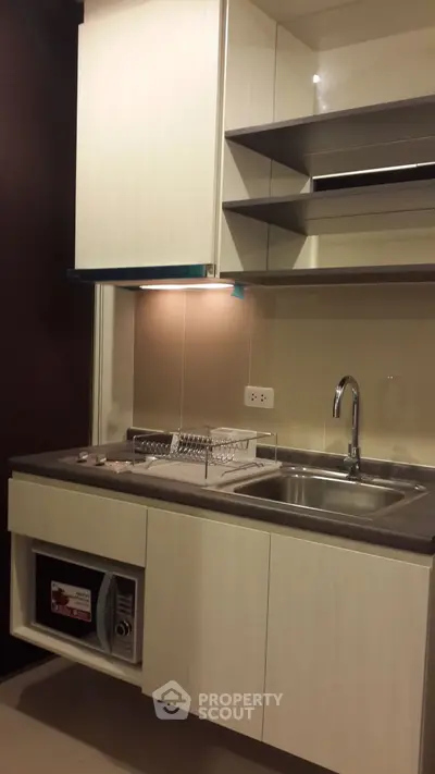 Modern kitchen with sleek cabinetry and stainless steel sink in a compact layout.