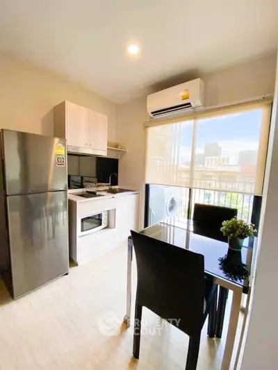Modern kitchen with dining area, featuring stainless steel appliances and city view.