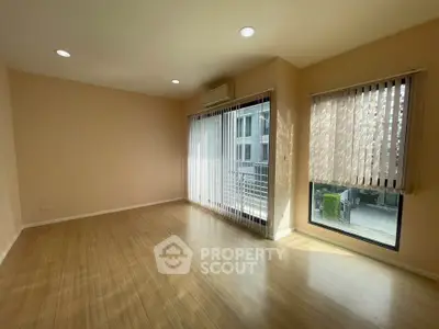 Spacious empty living room with large windows and wooden flooring in modern apartment.