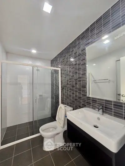 Modern bathroom with sleek black tiles and glass shower enclosure