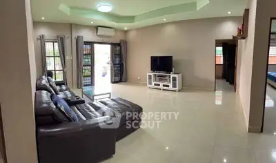 Spacious living room with modern leather sofa and large TV, perfect for relaxation.