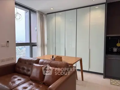 Modern living room with leather sofa and dining table near large window with city view.