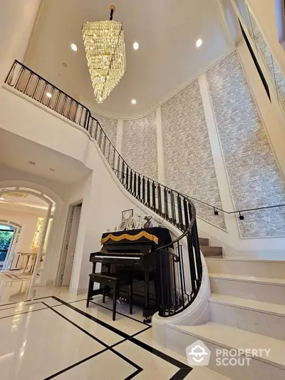 Luxurious foyer with grand staircase and elegant chandelier in upscale home