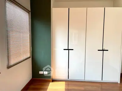 Modern bedroom with sleek white wardrobe and wooden flooring