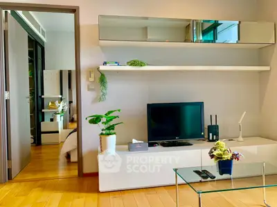 Modern living room with sleek furniture and wooden flooring, featuring a TV and stylish decor.