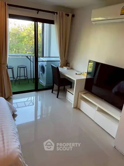 Modern bedroom with balcony, featuring a sleek TV, desk, and washing machine for convenient living.