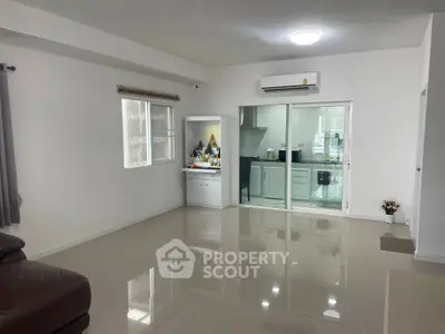 Spacious modern living room with glossy tiled floors and open kitchen view.