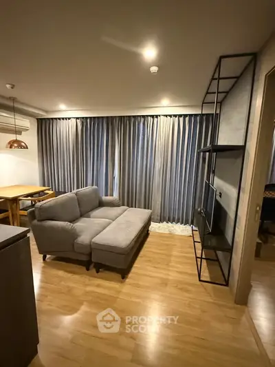 Modern living room with cozy gray sofa, wooden flooring, and elegant curtains in a stylish apartment.