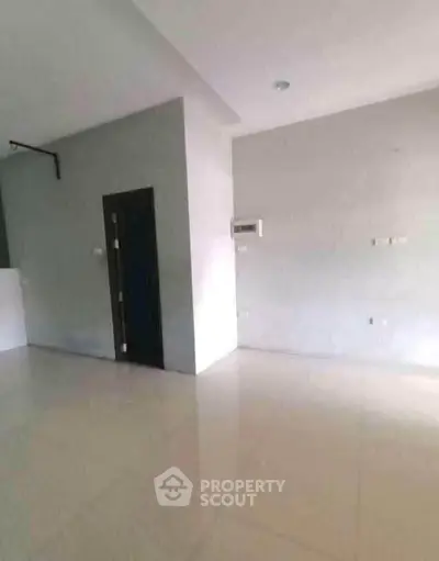 Spacious empty room with tiled flooring and neutral walls, ready for customization.