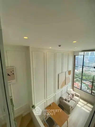 Modern living room with large windows offering stunning city views, featuring elegant decor and cozy seating area.