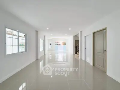 Spacious modern living room with glossy tiled floors and ample natural light.