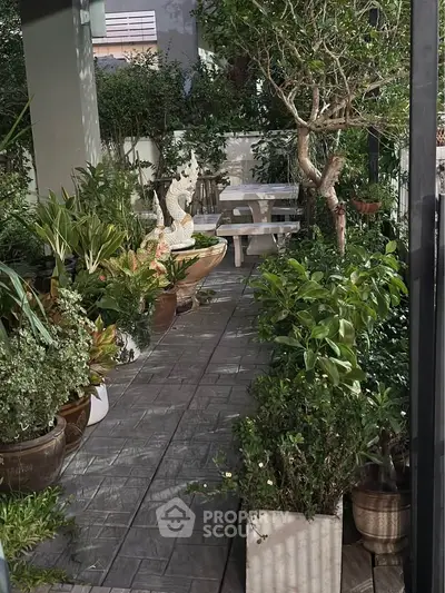 Charming garden patio with lush greenery and cozy seating area, perfect for relaxation and outdoor enjoyment.