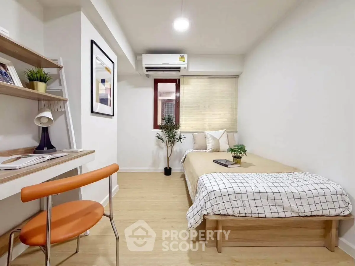 Modern minimalist bedroom with study area, featuring sleek furniture and cozy decor.