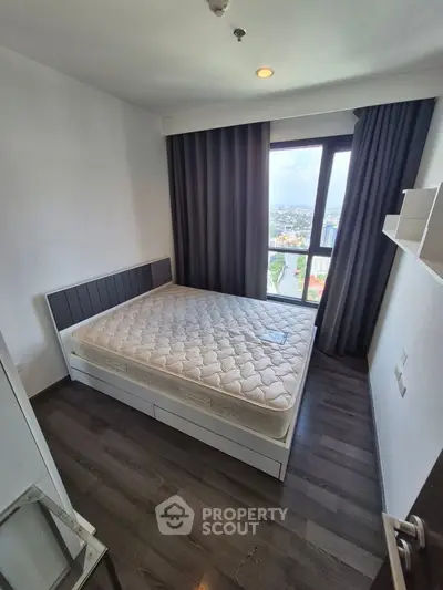 Modern bedroom with large window and city view, featuring a comfortable bed and stylish flooring.