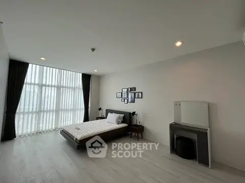 Spacious minimalist bedroom with large window and modern decor