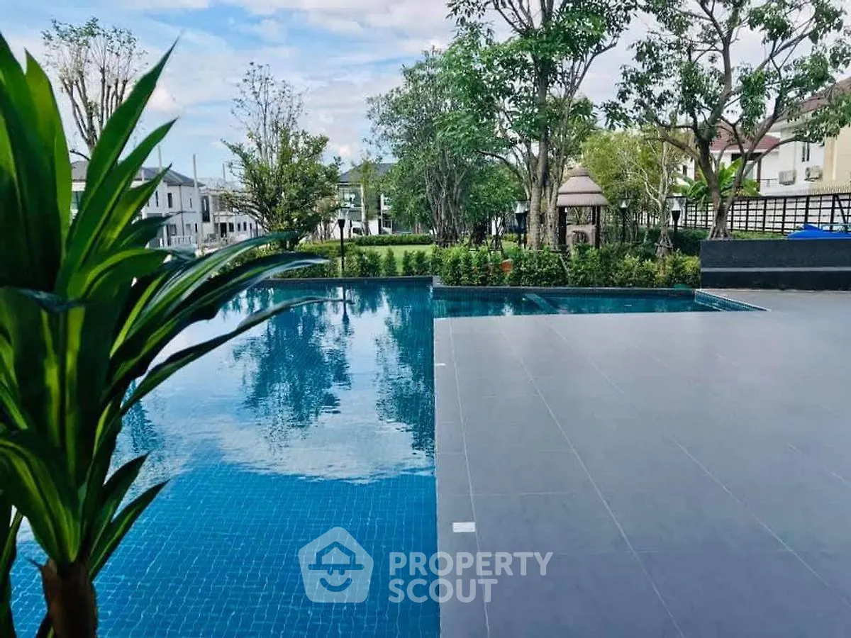 Luxurious outdoor pool area with serene garden views in upscale residential community.