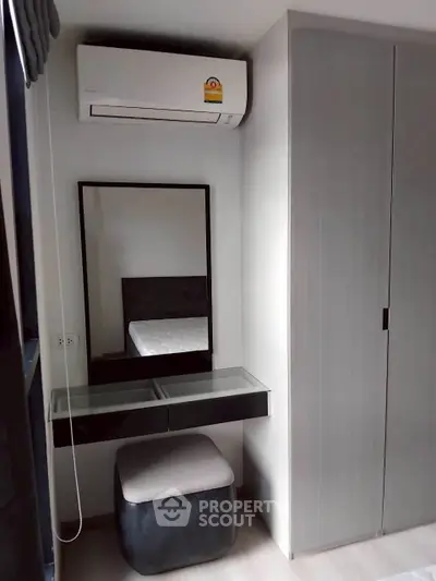 Modern bedroom with sleek wardrobe and air conditioning unit, featuring a stylish vanity area.