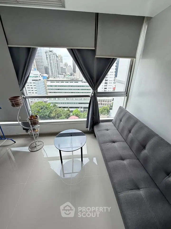 Modern living room with city view, featuring sleek gray sofa and stylish decor.