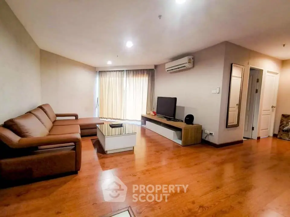 Spacious living room with modern furniture and wooden flooring in a cozy apartment.