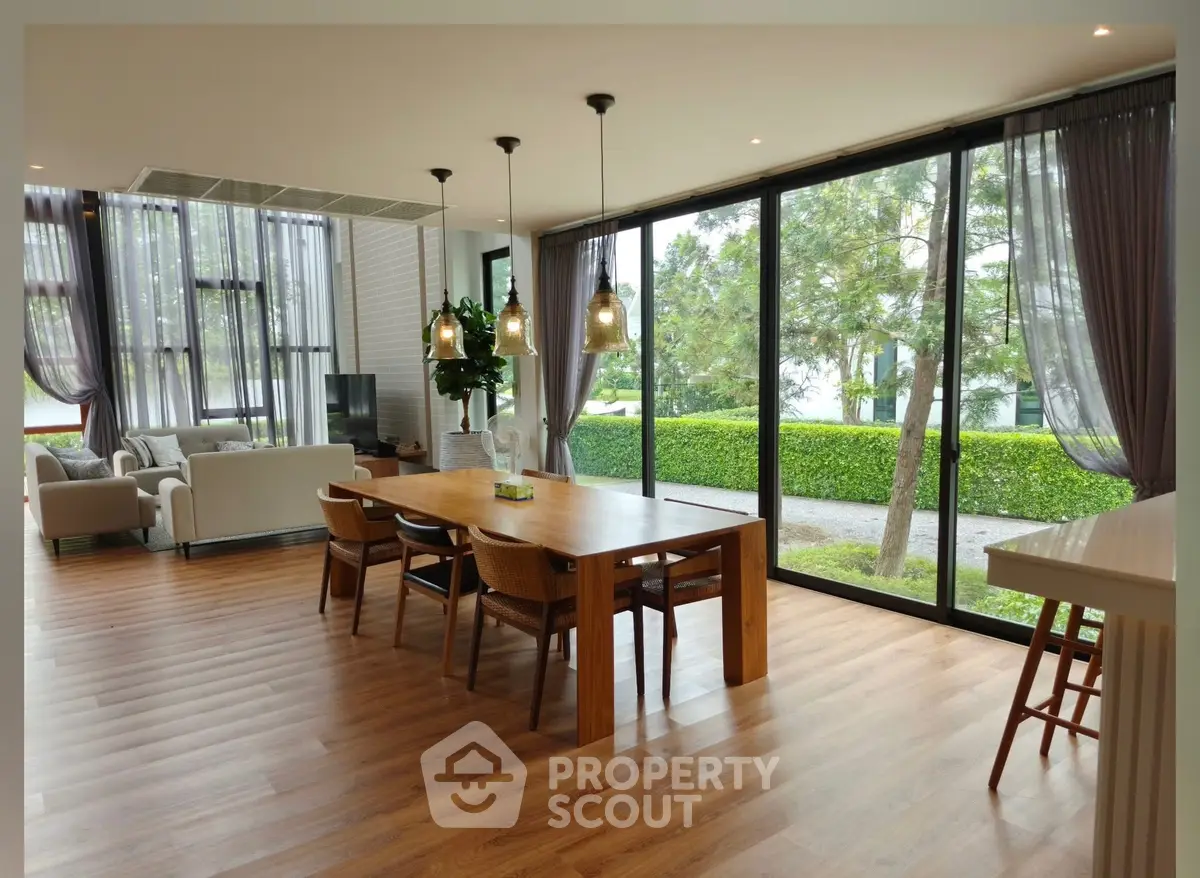 Spacious modern living room with large windows and garden view, featuring elegant dining area.