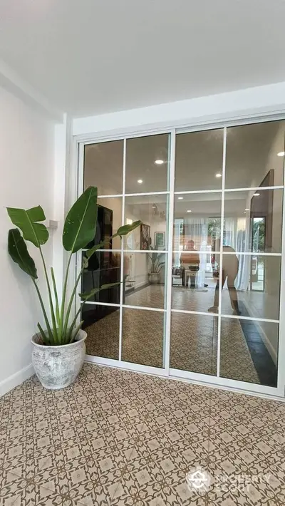 Stylish interior with large mirror doors and decorative plant in modern living space.