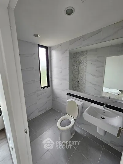 Modern bathroom with sleek tiles and large window for natural light.