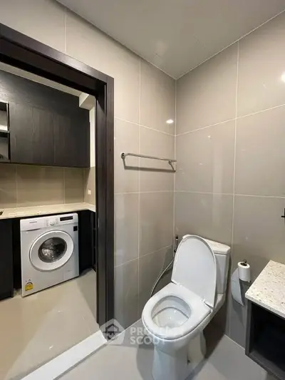 Modern bathroom with sleek design and adjacent laundry area featuring a washing machine.