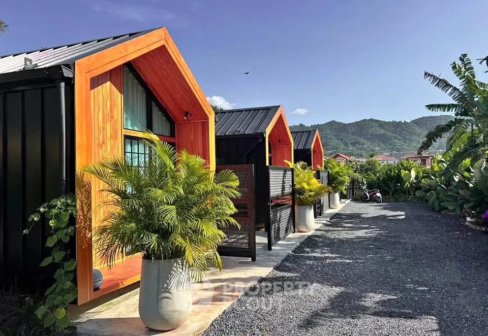 Charming modern tiny homes with vibrant facades and lush greenery in a serene mountain setting.