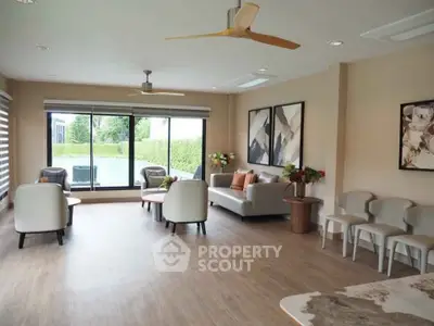 Spacious modern living room with elegant decor and large windows overlooking greenery.