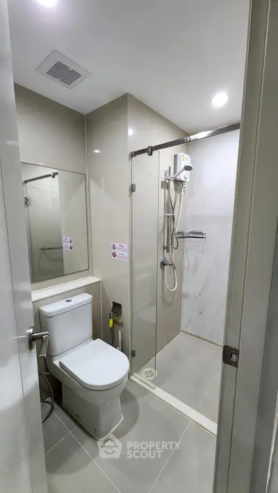 Modern bathroom with glass shower and sleek fixtures in a contemporary home.