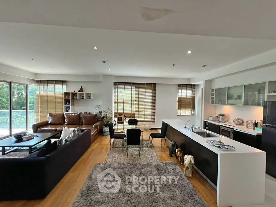 Spacious open-plan living room with modern kitchen and large windows offering natural light.