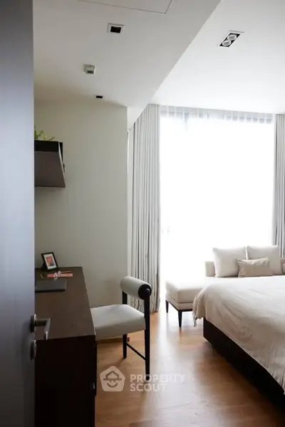 Modern bedroom with elegant decor and natural light, featuring a cozy bed and stylish desk.
