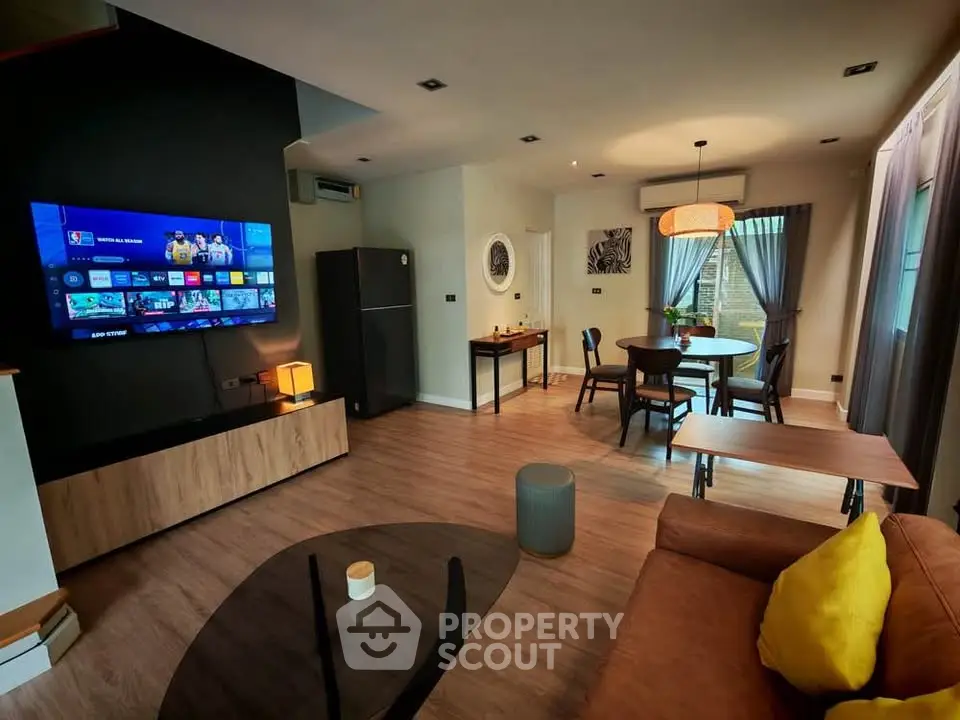 Modern living room with open layout, stylish furniture, and large TV for entertainment.