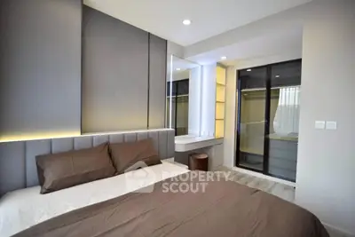 Modern bedroom with sleek design and large mirror, featuring neutral tones and cozy ambiance.