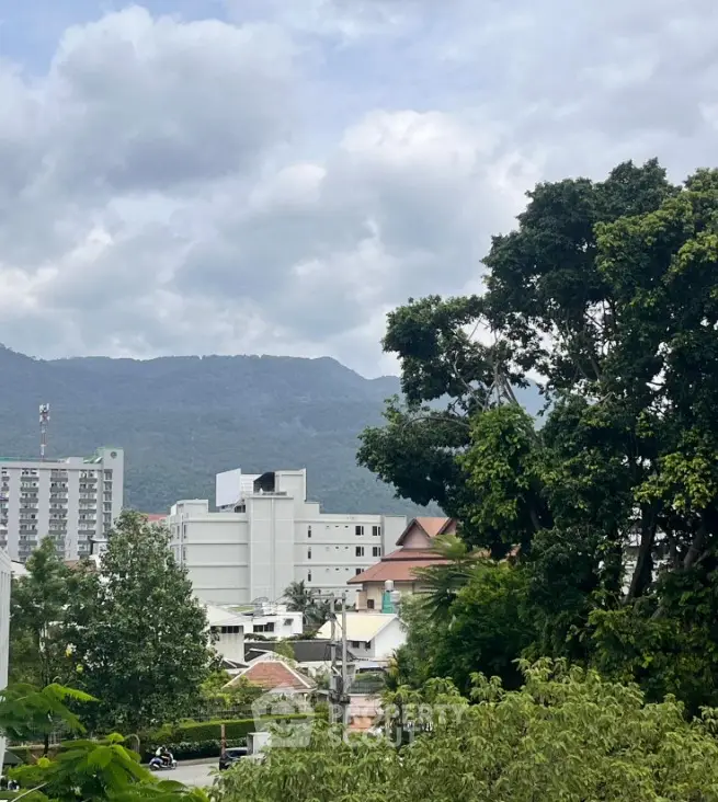 Scenic view of urban landscape with mountains and lush greenery