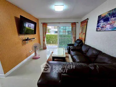 Stylish living room with leather sofa and wall-mounted TV, featuring large windows and modern decor.